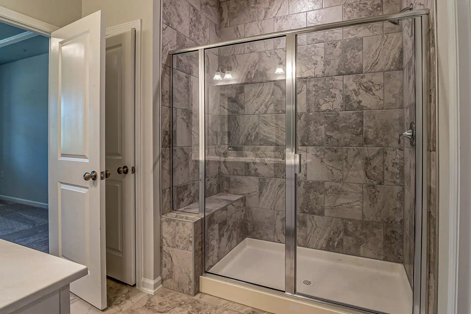 Marble-look tiled shower with a glass door (representative photo)