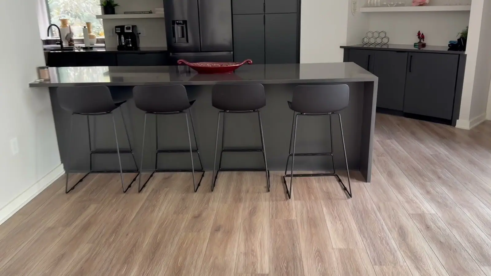 Charcoal waterfall island with four stools in a finished kitchen